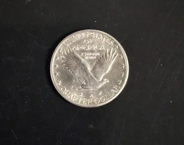 A coin that is on the ground in front of a black background.